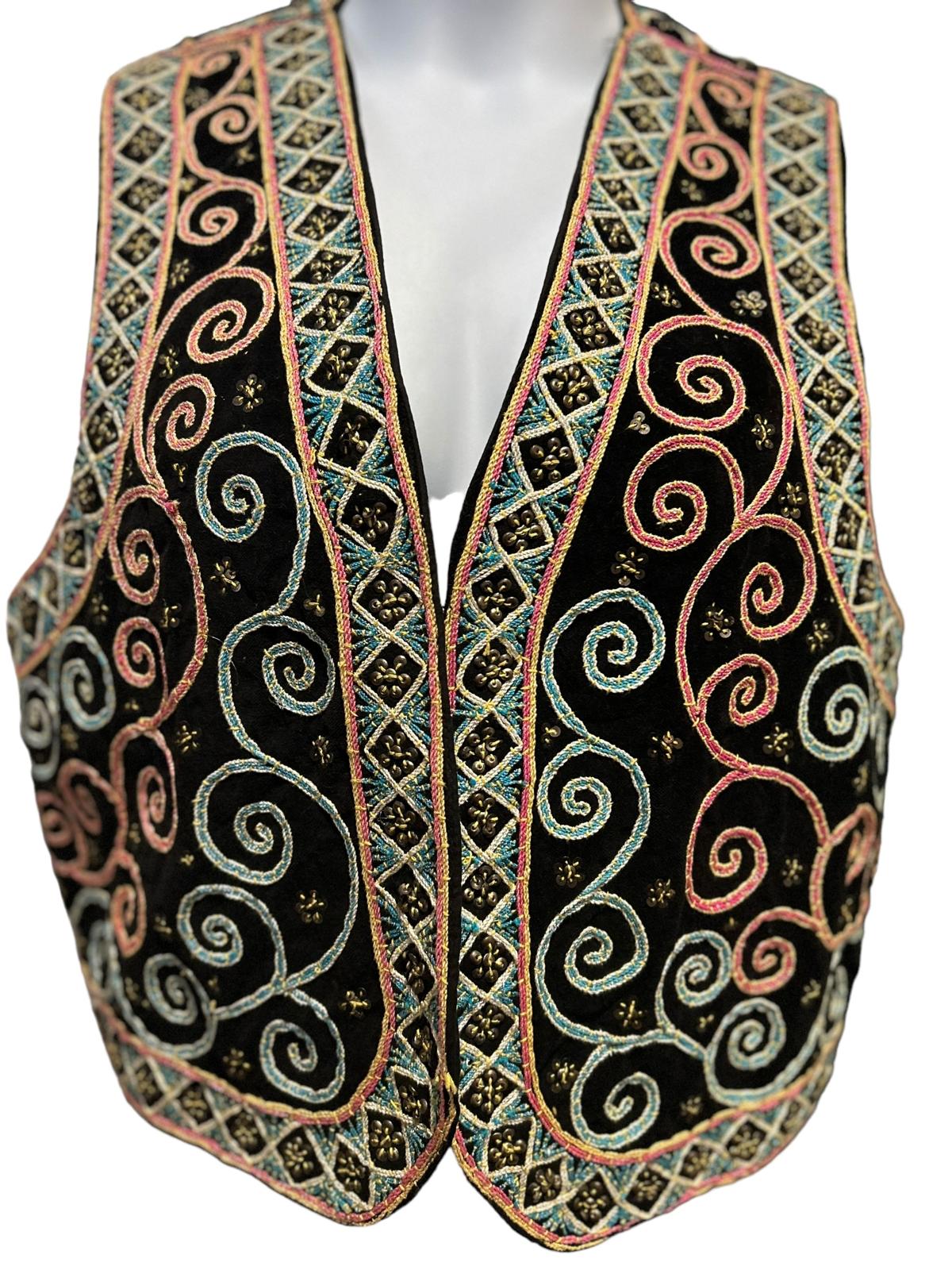 This vintage beaded vest by Carol Horn is a one-of-a-kind piece from the 1970s. The vest boasts a unique elephant motif, intricately hand-beaded with shimmering beads and sequins. The soft, black fabric and the slightly cropped fit add to its allure. The vest is designed for easy wear with a front hook-and-eye closure.   This vintage Carol Horn beaded vest with elephants is a statement piece that will confidently make a stylish impact. It is perfect for adding a bohemian flair to any outfit.